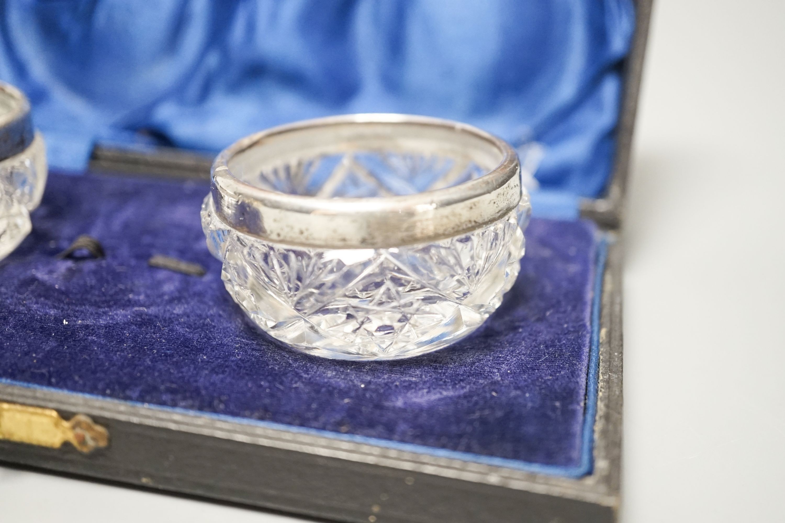 Two early 20th century Russian white metal tots, a sterling beaker, white metal double measure and a case pair of silver mounted glass salts.